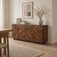 Sideboard with a carved branching tree relief across four front panels in a Scandinavian dining room with white walls