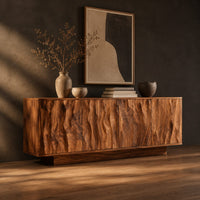 Low sideboard with four tall doors carved in a rippled flowing pattern, three-quarter view showing the grain