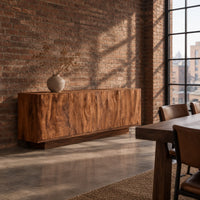 Low sideboard with four tall doors carved in a rippled flowing pattern in an industrial loft dining room with exposed brick