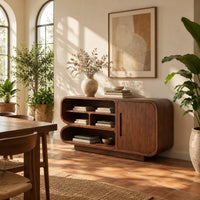Sideboard with three tiers of open shelves beside a single slot pull door in a bright dining room with arched windows and plants