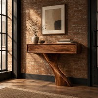 Console table with a slim box top and a single swept sculpted leg in an industrial loft entryway with exposed brick
