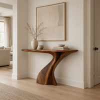 Console table on a single sculpted pedestal that twists up to the top in a Scandinavian entryway with white walls