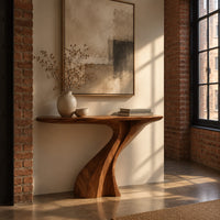 Console table on a single sculpted pedestal that twists up to the top in an industrial loft entryway with exposed brick