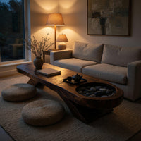 Long dark slab coffee table with a carved bowl in an evening room lit by two lamps