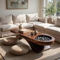 Long dark slab coffee table with a carved bowl in a sunlit room with large windows and plants