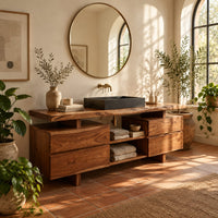 Slab top bathroom vanity with two drawer stacks and an open towel shelf in a bright bathroom with arched windows and plants