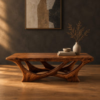 Slab top coffee table on a branching base of crossing curved arms in a dark studio against a charcoal plaster wall