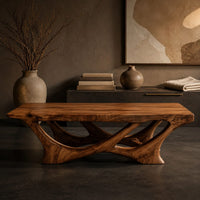 Corner detail of slab top coffee table on a branching base of crossing curved arms beside wood, brass and linen samples