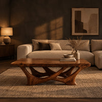 Slab top coffee table on a branching base of crossing curved arms in a dark living room at golden hour