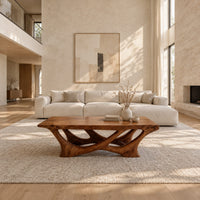 Slab top coffee table on a branching base of crossing curved arms in a bright open plan living room