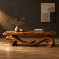Slab top coffee table on a swooping wave shaped base in a dark studio against a charcoal plaster wall