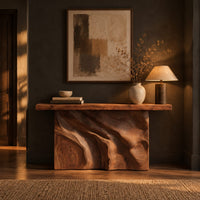 Slab console table on a swirling carved block base in a dark entryway at golden hour