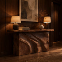 Slab console table on a swirling carved block base in an evening entryway with walnut wall paneling