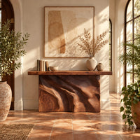 Slab console table on a swirling carved block base in a bright entryway with arched windows and plants