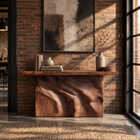 Slab console table on a swirling carved block base in an industrial loft entryway with exposed brick
