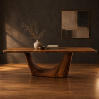 Rectangular dining table with a thick top on one deep crescent pedestal in a dark studio against a charcoal plaster wall