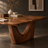 Corner detail of rectangular dining table with a thick top on one deep crescent pedestal beside wood, brass and linen samples