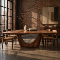 Rectangular dining table with a thick top on one deep crescent pedestal in an industrial loft dining room with exposed brick