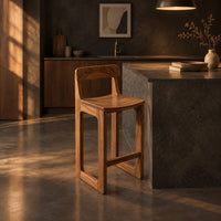 Bar stool with a low back, scooped seat and sled style legs in a dark kitchen at golden hour