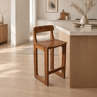 Bar stool with a low back, scooped seat and sled style legs in a Scandinavian kitchen with white walls