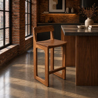 Bar stool with a low back, scooped seat and sled style legs in an industrial loft kitchen with exposed brick