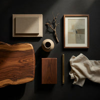 Corner detail of sled side coffee table with a floating lower shelf beside wood, brass and linen samples
