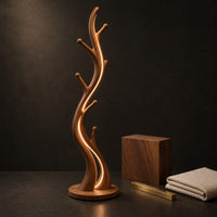Corner detail of slim floor lamp shaped like a branching tree with glowing lines beside wood, brass and linen samples