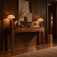Slim console table with three front panels and tapered legs in an evening entryway with walnut wall paneling