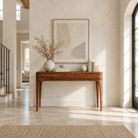 Slim console table with three front panels and tapered legs in a bright open plan entryway