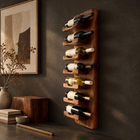 Corner detail of slim vertical wine rack with seven angled cradles on a tall wooden board beside wood, brass and linen samples