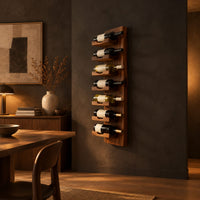 Slim vertical wine rack with seven angled cradles on a tall wooden board in a dark dining room at golden hour