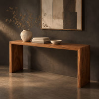 Corner detail of slim waterfall console table with a smooth top and two wide slab legs beside wood, brass and linen samples