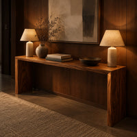 Slim waterfall console table with a smooth top and two wide slab legs in an evening entryway with walnut wall paneling
