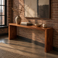 Slim waterfall console table with a smooth top and two wide slab legs in an industrial loft entryway with exposed brick