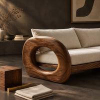 Corner detail of wood sofa with open ring arms and two wide seat cushions beside wood, brass and linen samples