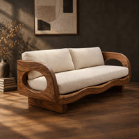 Sofa with oval arm openings, a wavy wooden frame and pale seat cushions, three-quarter view showing the grain