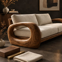Corner detail of sofa with thick open loop wooden arms and two seat cushions beside wood, brass and linen samples