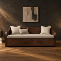 Wood sofa with sweeping arms and a deep paneled base in a dark studio against a charcoal plaster wall