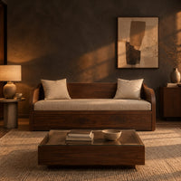 Wood sofa with sweeping arms and a deep paneled base in a dark living room at golden hour