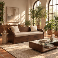 Wood sofa with sweeping arms and a deep paneled base in a bright living room with arched windows and plants