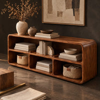 Corner detail of open console table with soft edges and a long shelf above three cubbies beside wood, brass and linen samples