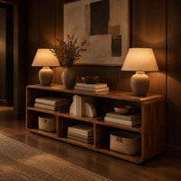 Open console table with soft edges and a long shelf above three cubbies in an evening entryway with walnut wall paneling