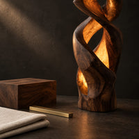 Corner detail of floor lamp carved as a twisting solid column with glowing cutouts beside wood, brass and linen samples