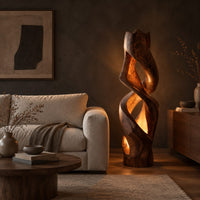 Floor lamp carved as a twisting solid column with glowing cutouts in a dark living room at golden hour