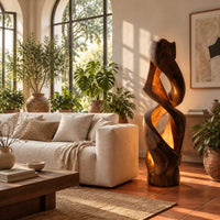 Floor lamp carved as a twisting solid column with glowing cutouts in a bright living room with arched windows and plants