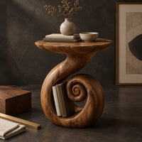Corner detail of round side table with a swirling stem and a coiled spiral base beside wood, brass and linen samples