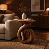 Round side table with a swirling stem and a coiled spiral base in an evening living room with walnut wall paneling