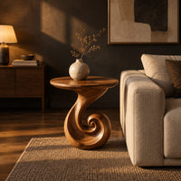 Scroll base side table with a circular top and spiral foot in a dark living room at golden hour