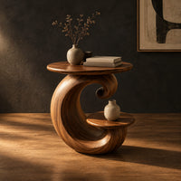 Spiral side table with a curled base and a small lower shelf in a dark studio against a charcoal plaster wall
