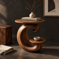 Corner detail of spiral side table with a curled base and a small lower shelf beside wood, brass and linen samples